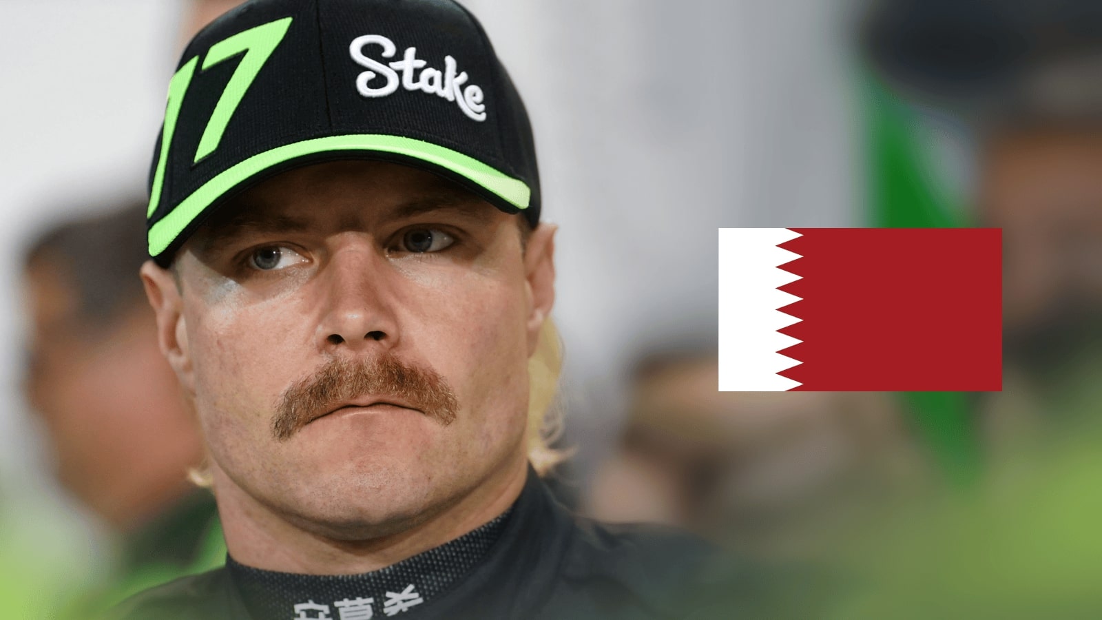 A close-up shot of Valtteri Bottas looking concerned with a prominent flag of Bahrain alongside him