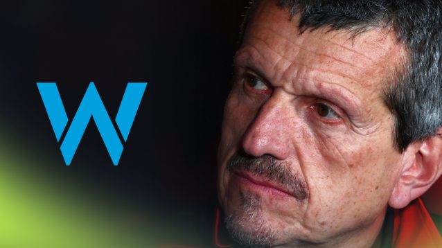 A close-up shot of Guenther Steiner looking to his right where a prominent Williams logo sits alongside him