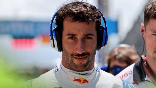 Daniel Ricciardo wearing headphones as he looks down the barrel of the camera lens in Barcelona