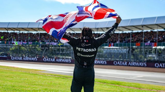 Lewis Hamilton holds up the British flag after winning the 2024 British Grand Prix.