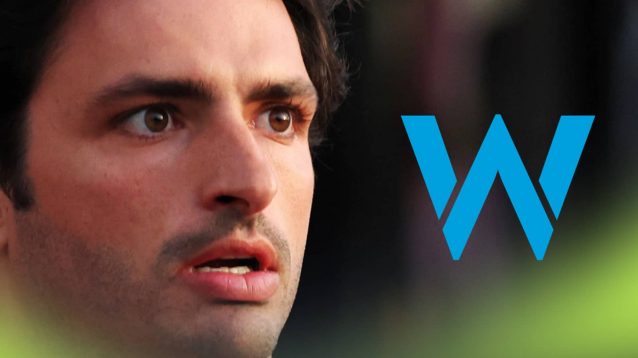 A close-up shot of a surprised Carlos Sainz with a prominent Williams logo alongside him