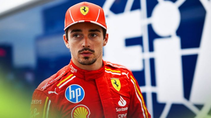 Charles Leclerc looks concerned as he makes his way through the paddock with an FIA truck in the background