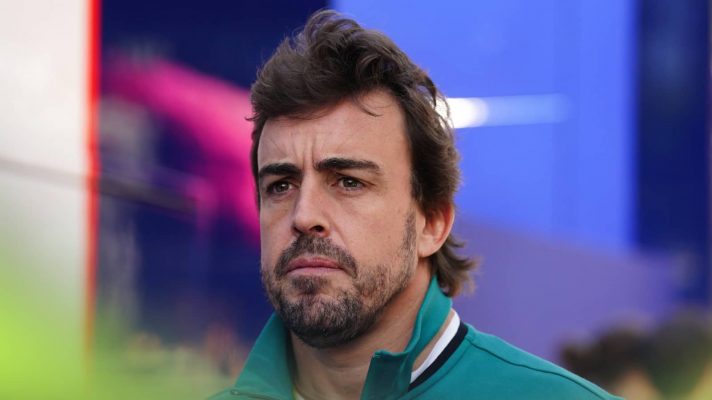 Fernando Alonso looks concerned as he makes his way through the paddock