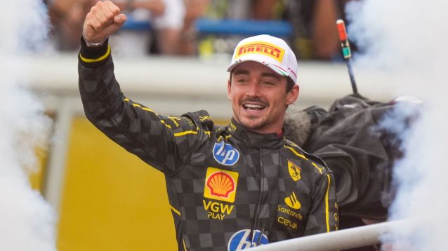 Charles Leclerc, fist raised, celebrates winning the 2024 Italian Grand Prix on the podium.