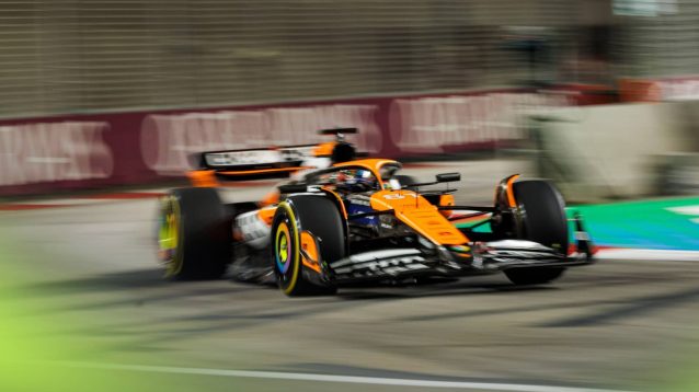 A blurry image of Oscar Piastri on track under the lights in Singapore