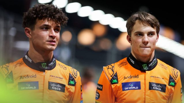 Lando Norris and Oscar Piastri stand together with uneasy facial expressions in the Singapore pit lane