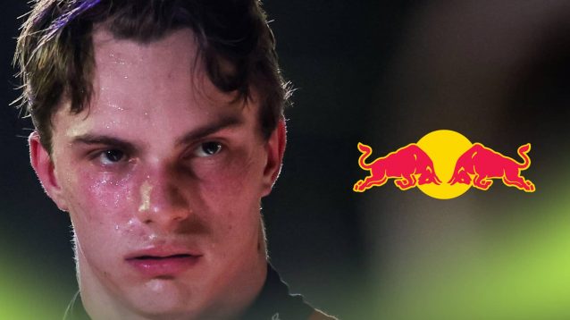 A close-up shot of Oscar Piastri looking annoyed with a Red Bull logo alongside him
