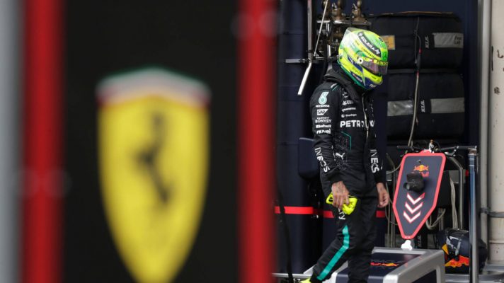 Lewis Hamilton with his head down as he walks down the pit lane