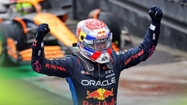 Max Verstappen raises his arms in celebration in parc ferme as Lando Norris's McLaren pulls up in the background