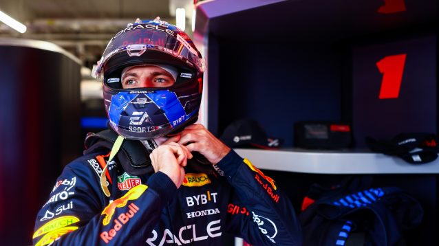 Max Verstappen fixes his helmet.
