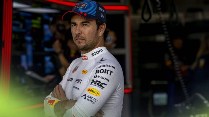 Sergio Perez stands with his arms folded outside the Red Bull garage