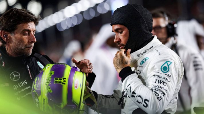 Lewis Hamilton is handed his helmet by a Mercedes team member on the grid in Qatar