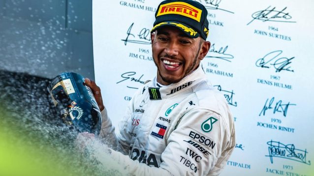 Lewis Hamilton smiles as he sprays champagne on the podium during his Mercedes career