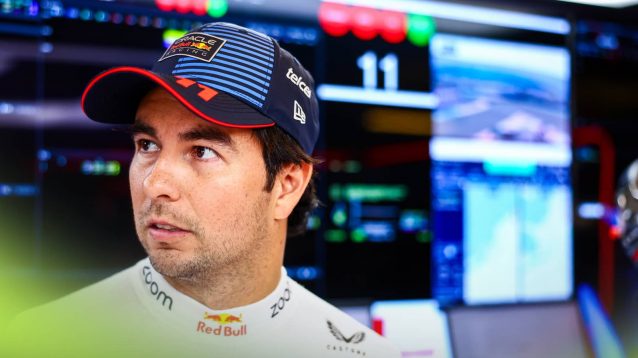 Sergio Perez looks on in the Red Bull garage with a bank of screens behind him
