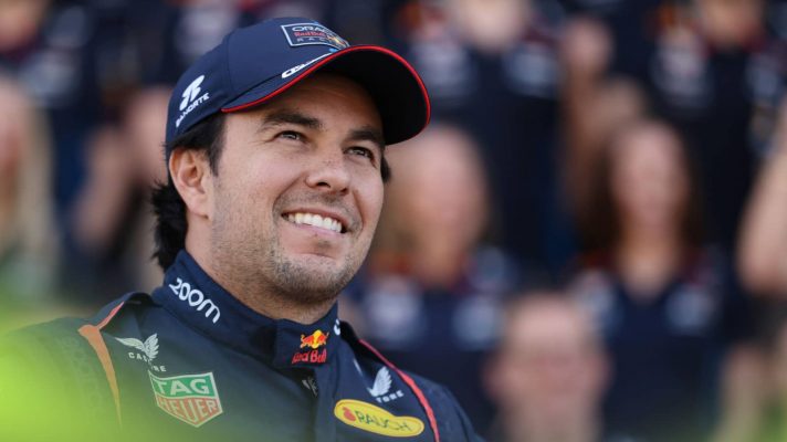 Sergio Perez smiles during Red Bull's end-of-season photocall with team members blurry in the background