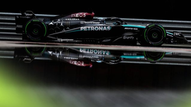 George Russell's Mercedes W15 is reflected in a puddle in the Silverstone pit lane
