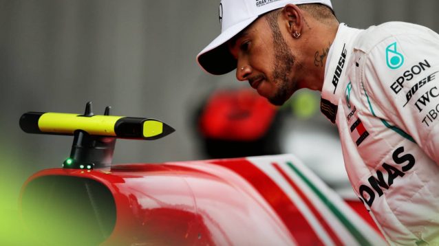 Lewis Hamilton studies a Ferrari F1 car in parc ferme during the 2018 season