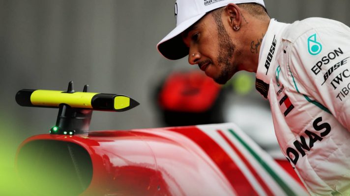 Lewis Hamilton studies a Ferrari F1 car in parc ferme during the 2018 season