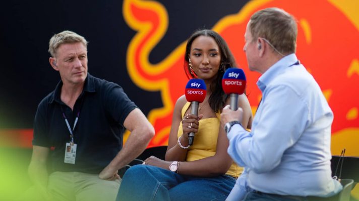 Simon Lazenby, Naomi Schiff and Martin Brundle sit on stools during a live Sky F1 broadcast with a Red Bull truck in the background