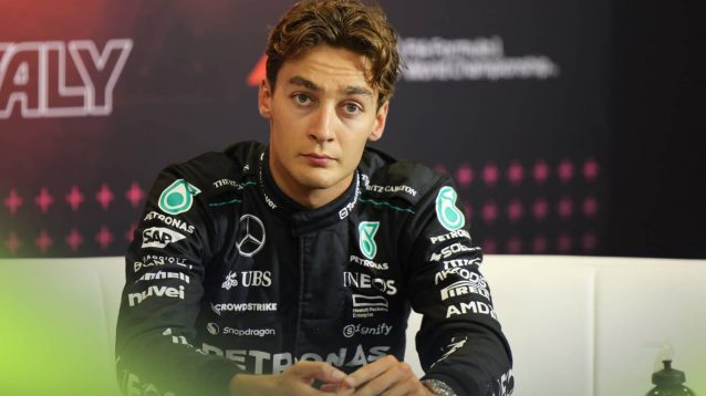George Russell looks frustrated while sitting in a press conference
