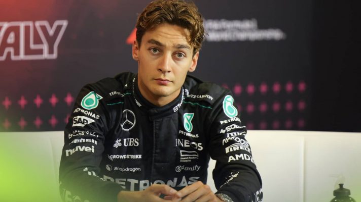 George Russell looks frustrated while sitting in a press conference
