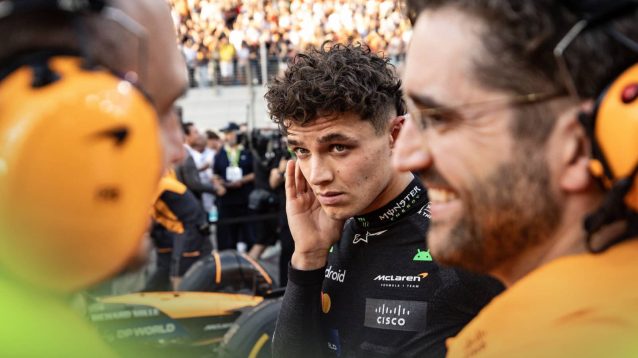 Lando Norris looks concerned on the Abu Dhabi grid as two McLaren mechanics smile
