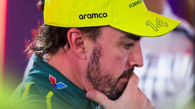 Fernando Alonso looks deep in thought with his hand pressed to his face
