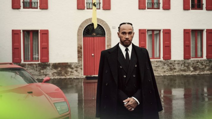 Lewis Hamilton posing outside of Enzo Ferrari's office at Maranello with a sepia-style tint