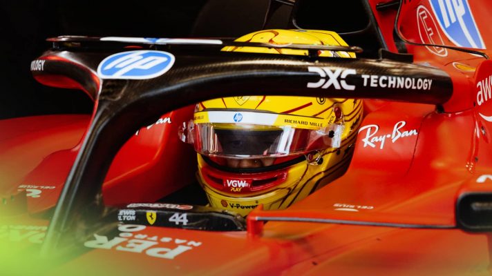 Lewis Hamilton wearing his new yellow helmet while seated in the cockpit of a Ferrari F1 car