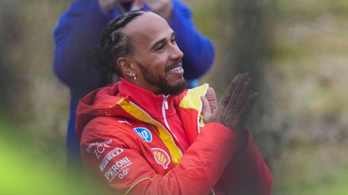 Lewis Hamilton smiles and holds his hands up in thanks to fans at Fiorano