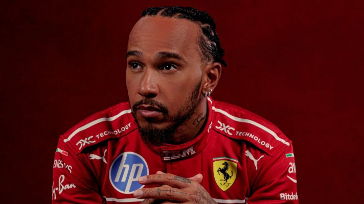 Lewis Hamilton poses while modelling Ferrari's 2025 race overalls