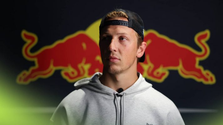 Liam Lawson poses in front of a giant Red Bull logo