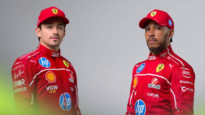 A studio shot of Charles Leclerc and Lewis Hamilton posing together in Ferrari overalls and caps