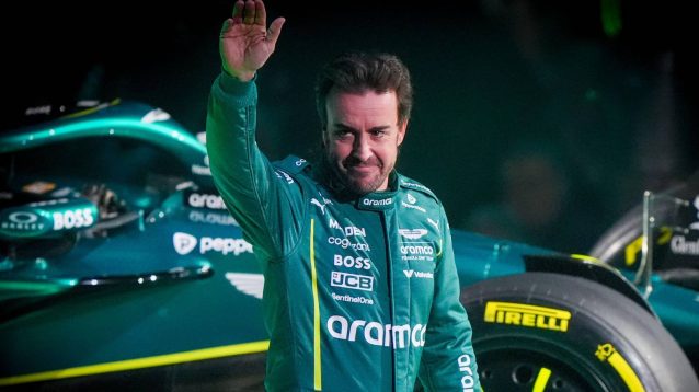 Aston Martin driver Fernando Alonso waves while stood in front of the AMR25 livery on display at the F1 75 season launch event in London