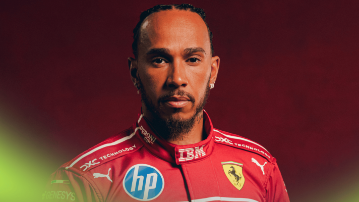 A studio shot of Lewis Hamilton posing in Ferrari overalls