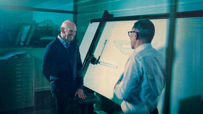 Adrian Newey smiles while standing alongside a drawing board in his new Aston Martin office