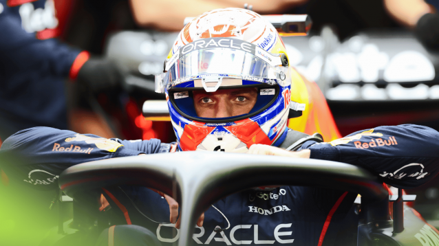 Max Verstappen looks straight ahead with his visor open as he climbs out of his car in the Red Bull garage