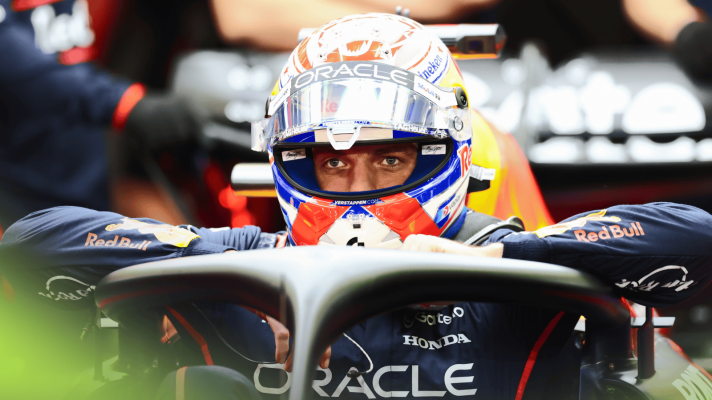 Max Verstappen looks straight ahead with his visor open as he climbs out of his car in the Red Bull garage