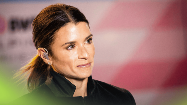 Danica Patrick smiles in the paddock with pink Alpine branding in the background