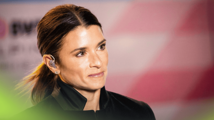 Danica Patrick smiles in the paddock with pink Alpine branding in the background
