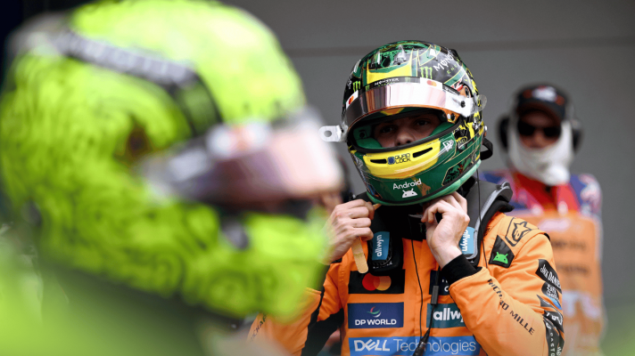 Oscar Piastri unfastens his helmet in parc ferme with Lando Norris's helmet in the foreground