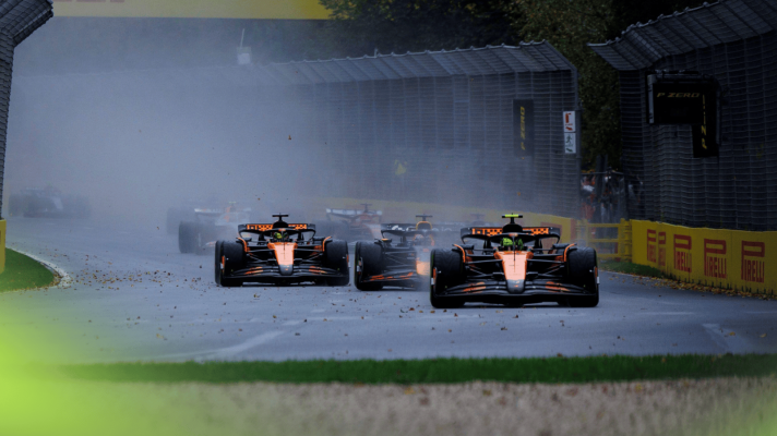Lando Norris's McLaren leads as the field approach Turn 3 at the start of the Australian GP with water spray being kicked up