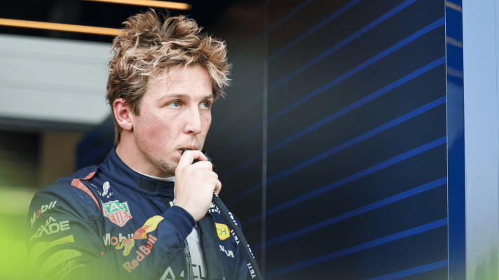 Liam Lawson drinks through a straw outside the Red Bull garage