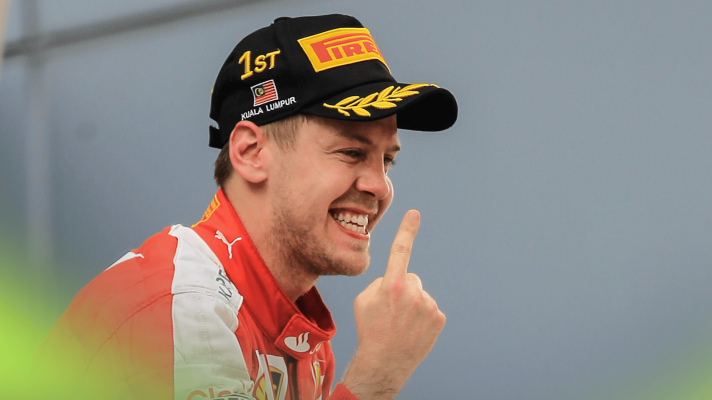 Sebastian Vettel smiles as he performs his iconic finger celebration on the 2015 Malaysian GP podium