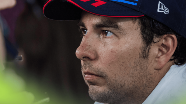 A close-up shot of Sergio Perez wearing a Red Bull cap with a towel draped around his neck