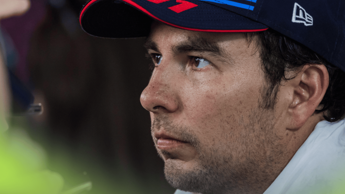 A close-up shot of Sergio Perez wearing a Red Bull cap with a towel draped around his neck