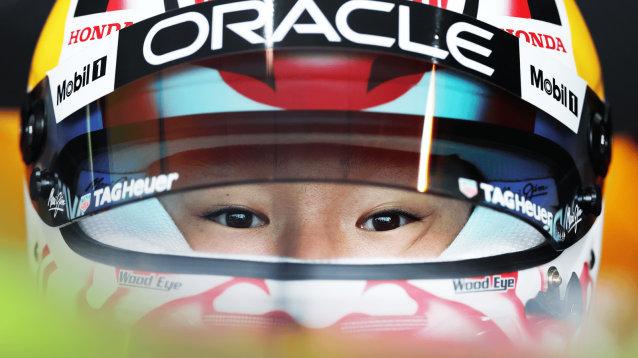 A close-up shot of Yuki Tsunoda with the visor of his helmet open