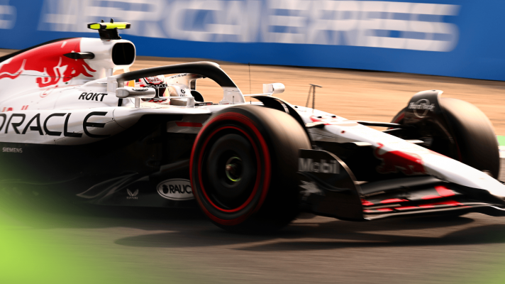 A dramatic shot of Yuki Tsunoda on track in his white-liveried Red Bull RB21 at Suzuka