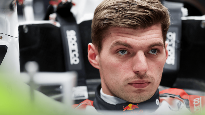 A close-up shot of Max Verstappen sitting in the Red Bull RB21 without his helmet in the garage