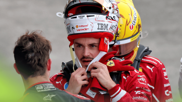 Charles Leclerc looks angry as he balances his helmet on his head in parc ferme